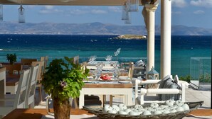 A seaside dining area with a table set for two, overlooking the ocean. - Saint George Hotel (Paros)