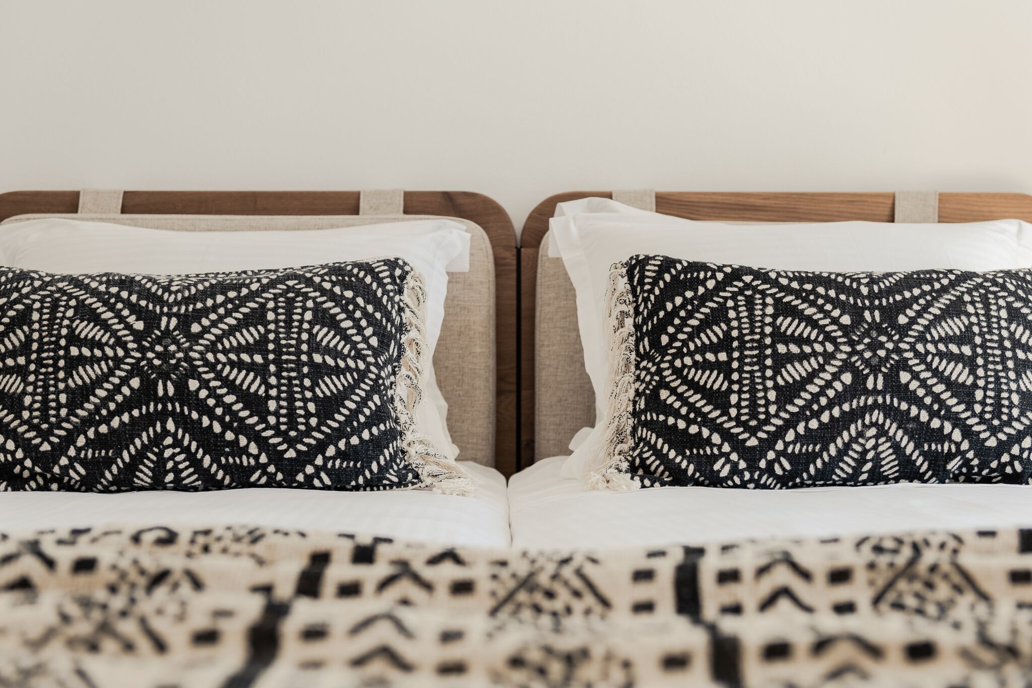 A bed with a patterned bedspread and two pillows with a geometric design.