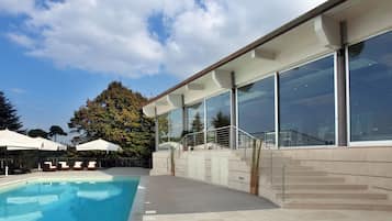 Una piscina al aire libre, sillones reclinables de piscina