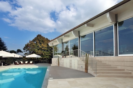 Una piscina al aire libre, sillones reclinables de piscina