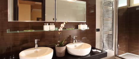 Un baño moderno con dos lavamanos, un espejo grande y cabina de ducha de vidrio.