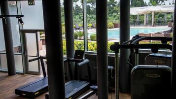 A gym with cardio equipment and a view of an outdoor swimming pool.
