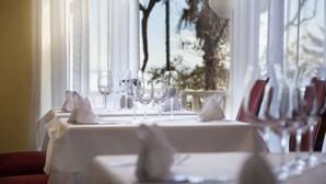 A dining table set with multiple wine glasses and napkins, with a view of trees and a railing in the background. - Hotel Kristal - Liburnia (Opatija)