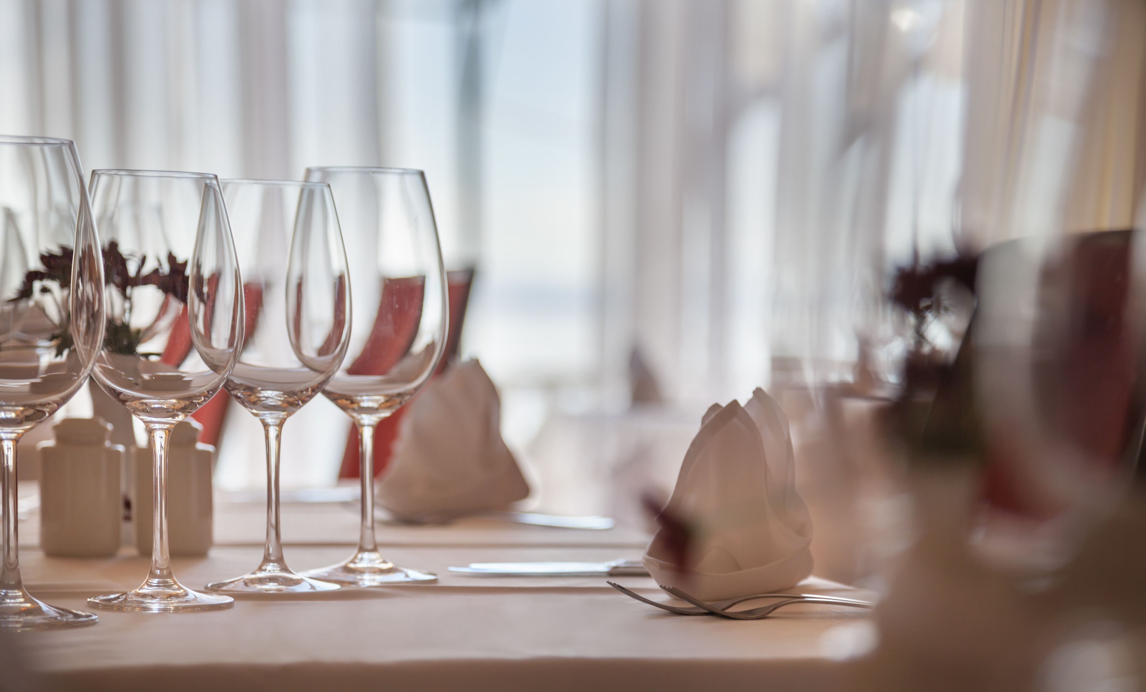 Ein Tisch mit mehreren leeren Weingläsern und einer einzelnen Blume.