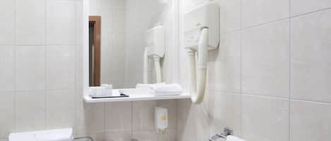 A bathroom with a white sink, a mirror, a towel rack, and a hairdryer mounted on the wall.