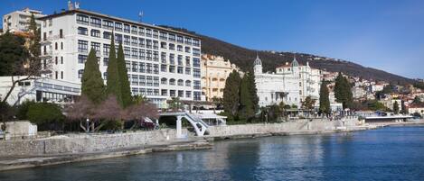 A waterfront hotel with a stone bridge, multiple floors, and a view of the river.