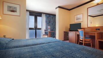 A hotel room with a bed, a desk, a chair, a television, and a window with curtains.