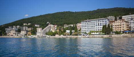 Un paisaje urbano frente al agua, con diversos edificios, incluyendo un hotel destacado de varios pisos y balcones.