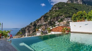 A clear blue pool with a view of a coastal town and a mountain in the background.