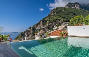 Una piscina al aire libre, sombrillas, sillones reclinables de piscina