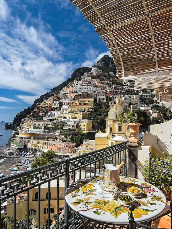 Enjoy a meal on the balcony overlooking the coastal town with its steep hillside and picturesque harbor.