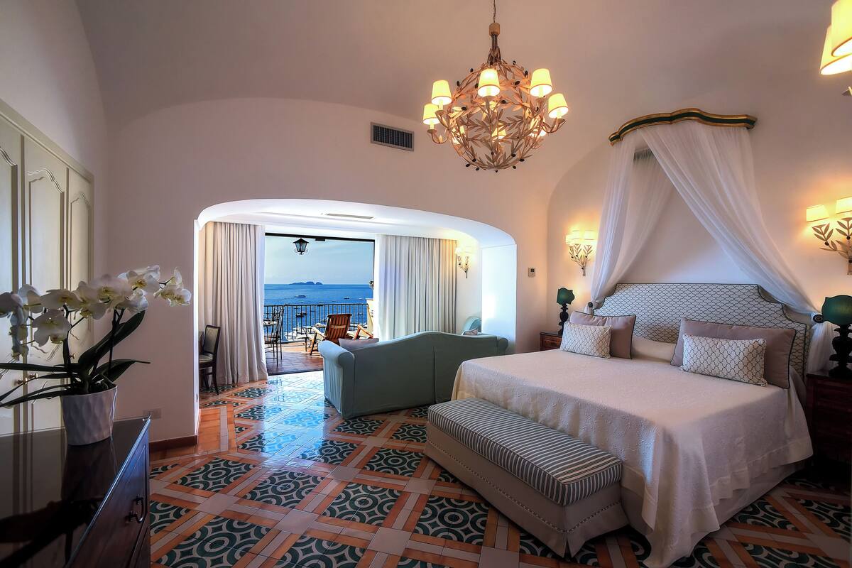 Un dormitorio amplio con una cama grande, un rincón de descanso y vistas al mar.