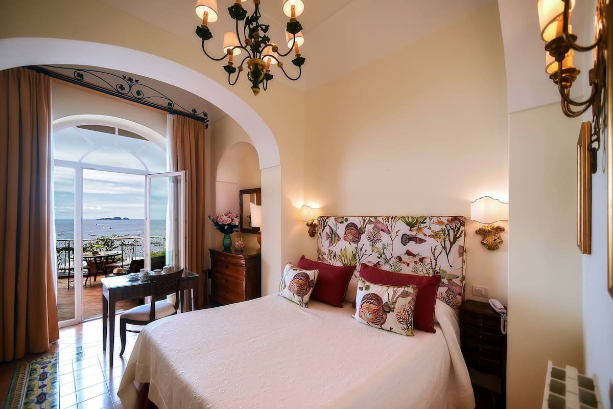 Habitación de hotel con cama, escritorio y vista al mar.