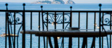 A view from a balcony with a railing, overlooking a body of water with boats and distant landforms.