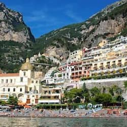 Explore a charming coastal town with a historic church and marina, set against a scenic rocky backdrop.