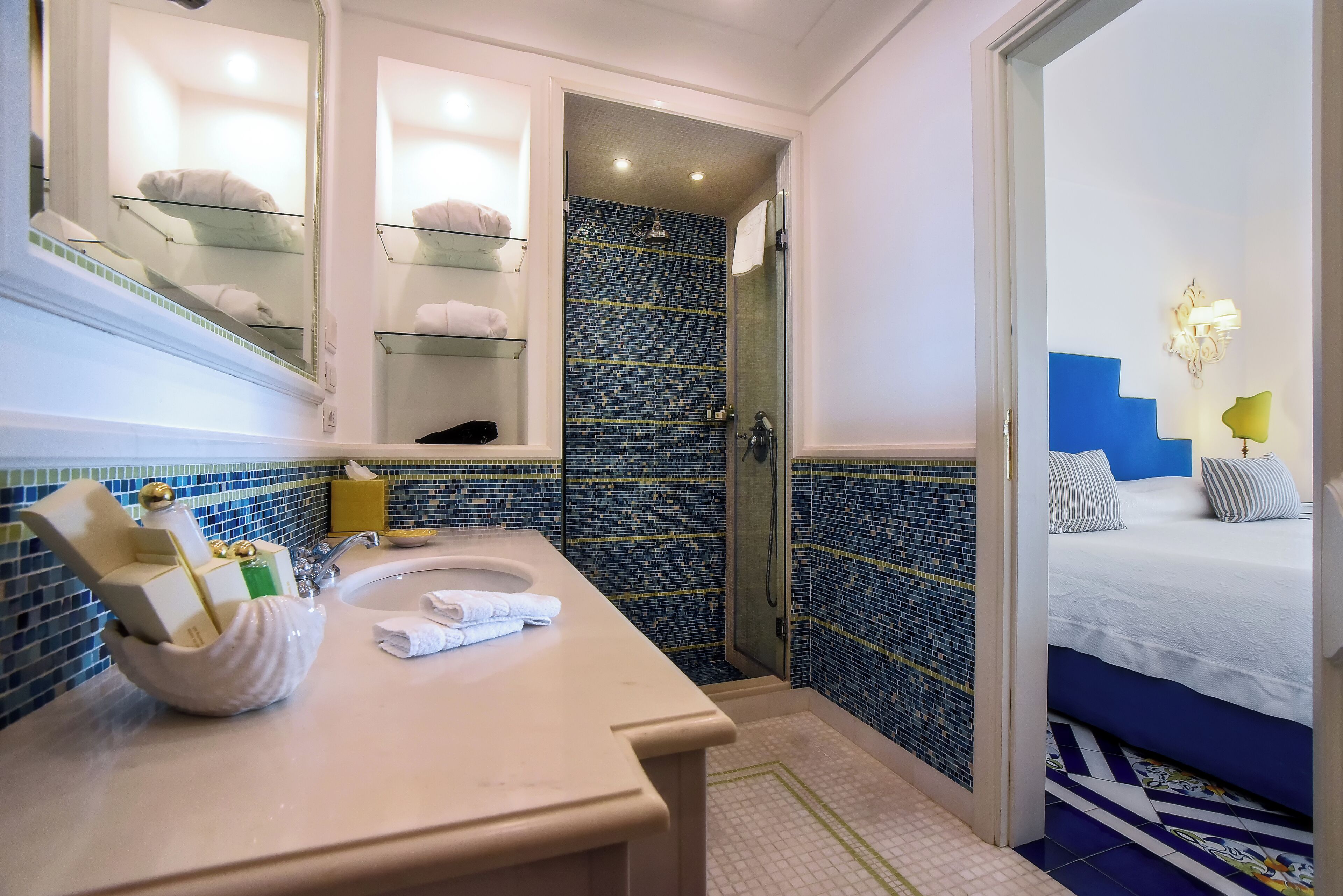 A bathroom with a sink, mirror, and glass shower enclosure.