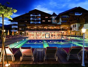 Un hotel con piscina, tumbonas y zona de estar exterior.