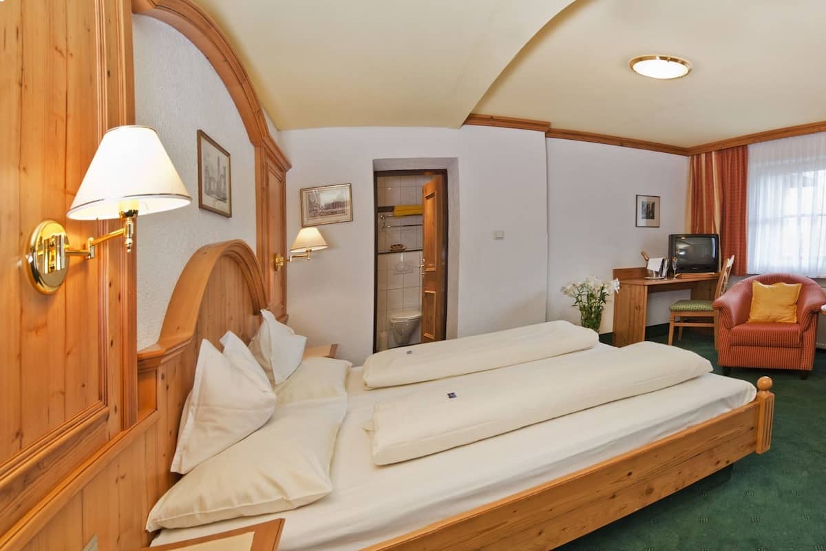 A hotel room with a double bed, a desk with a computer, a chair, and a television.