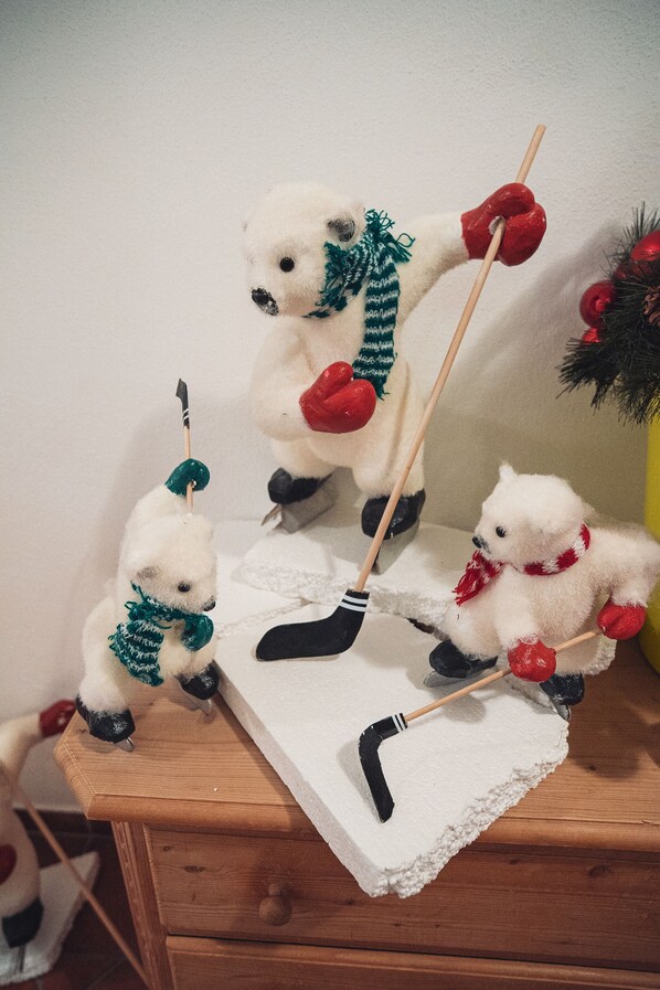 Un aparador de madera con tres ositos de peluche vestidos para el invierno, cada uno sosteniendo un stick de hockey.