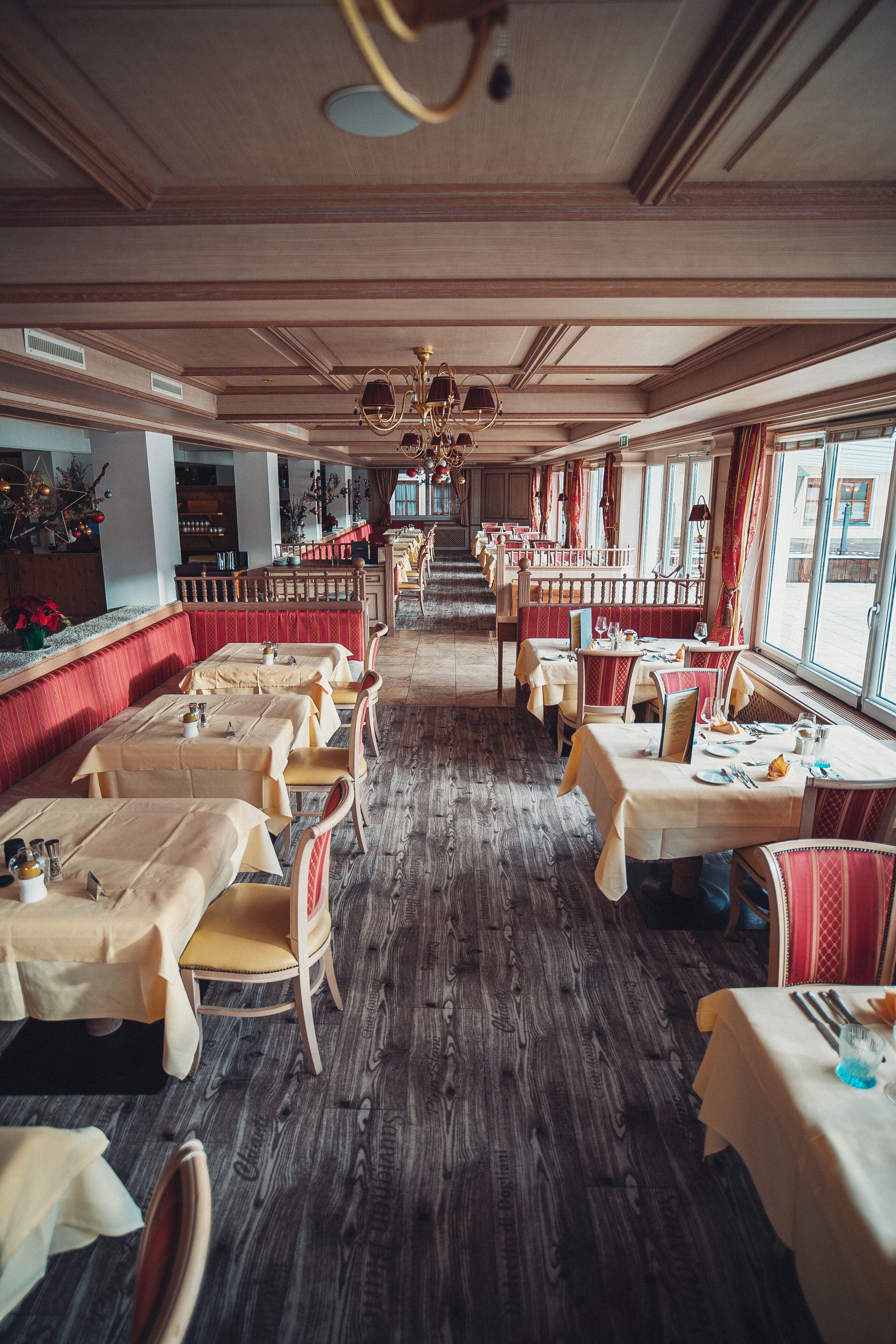 Un restaurante con suelos de madera, asientos tapizados en rojo y mesas dispuestas para comer.