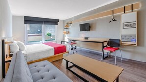 Una habitación de hotel moderna con una cama, un escritorio, un sofá y un televisor.