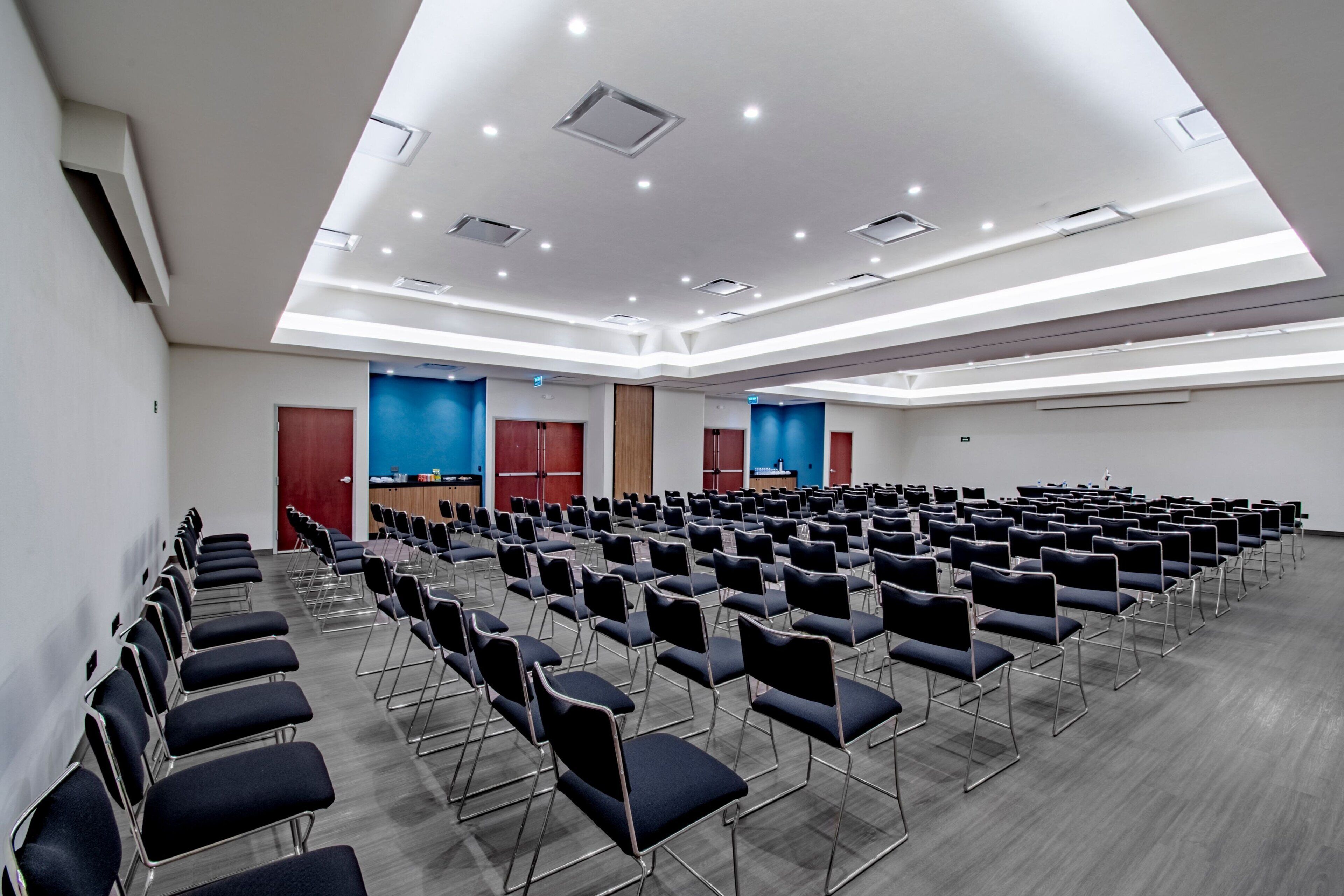 A conference room with rows of chairs, a podium, and blue accent walls.