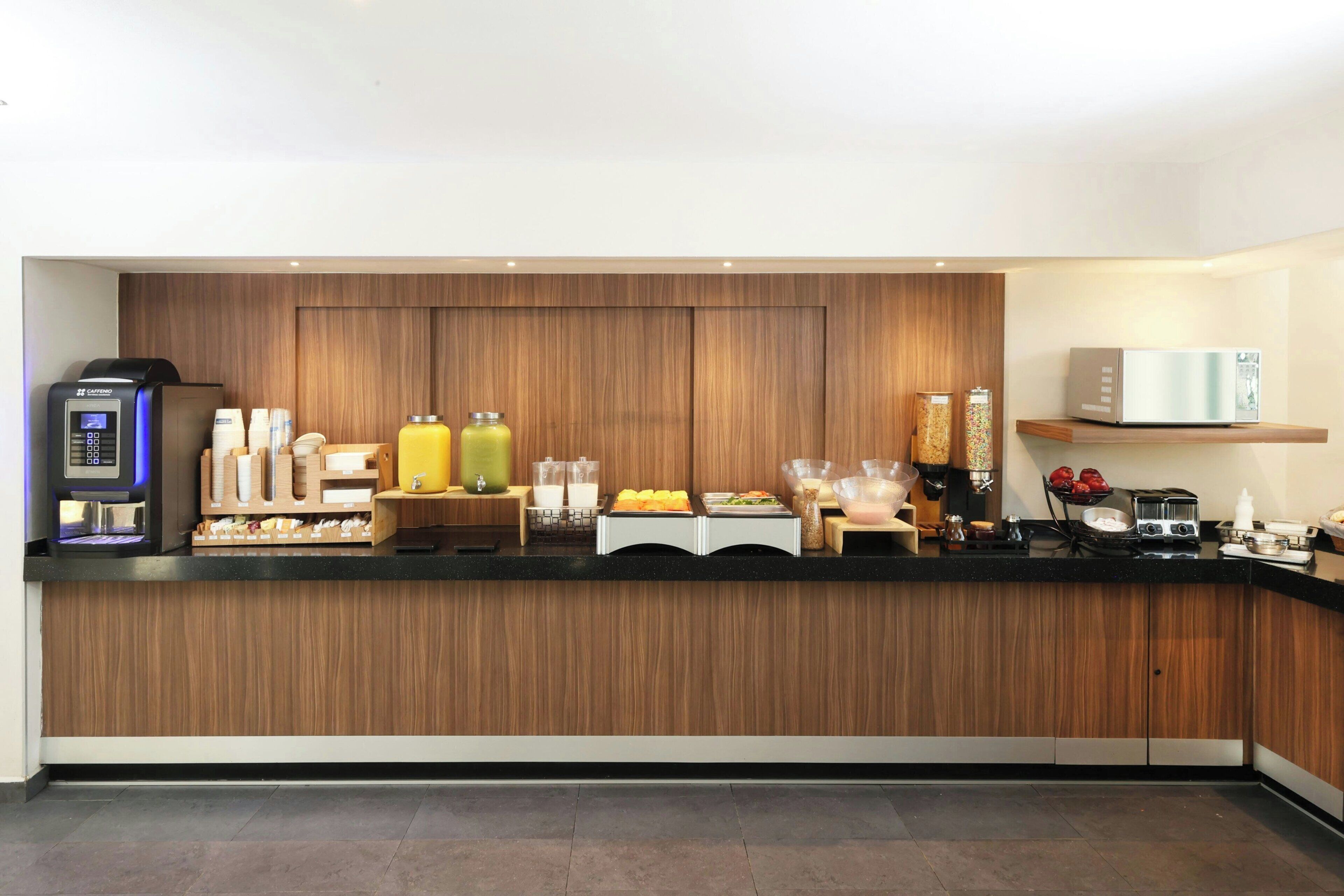 Une cuisine moderne équipée d’une machine à café, de distributeurs de jus et d’un four à micro-ondes.