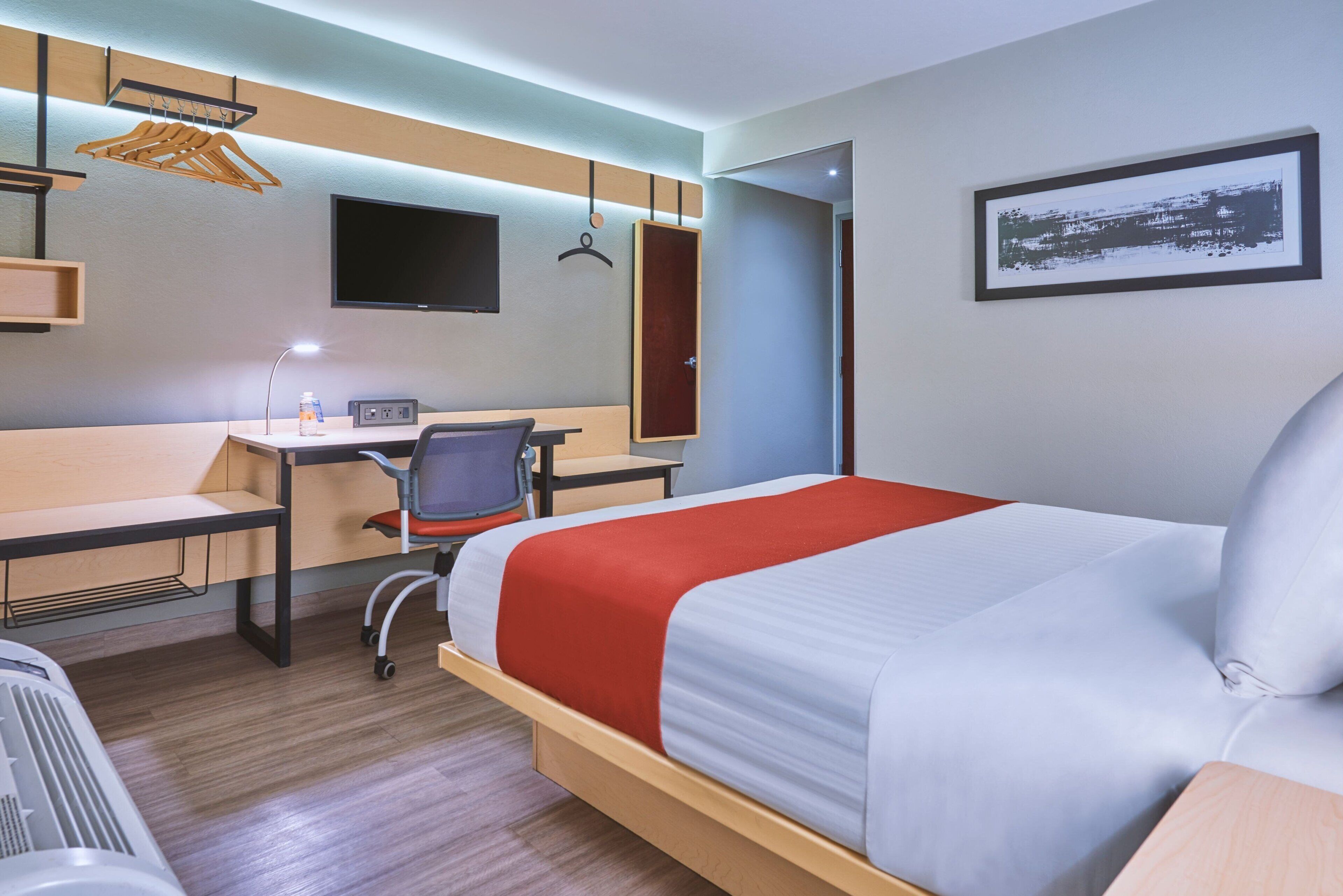 Una habitación de hotel con cama, escritorio, silla y televisor.