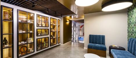 A modern interior with a seating area, a display of items in glass cabinets, and a patterned wall.