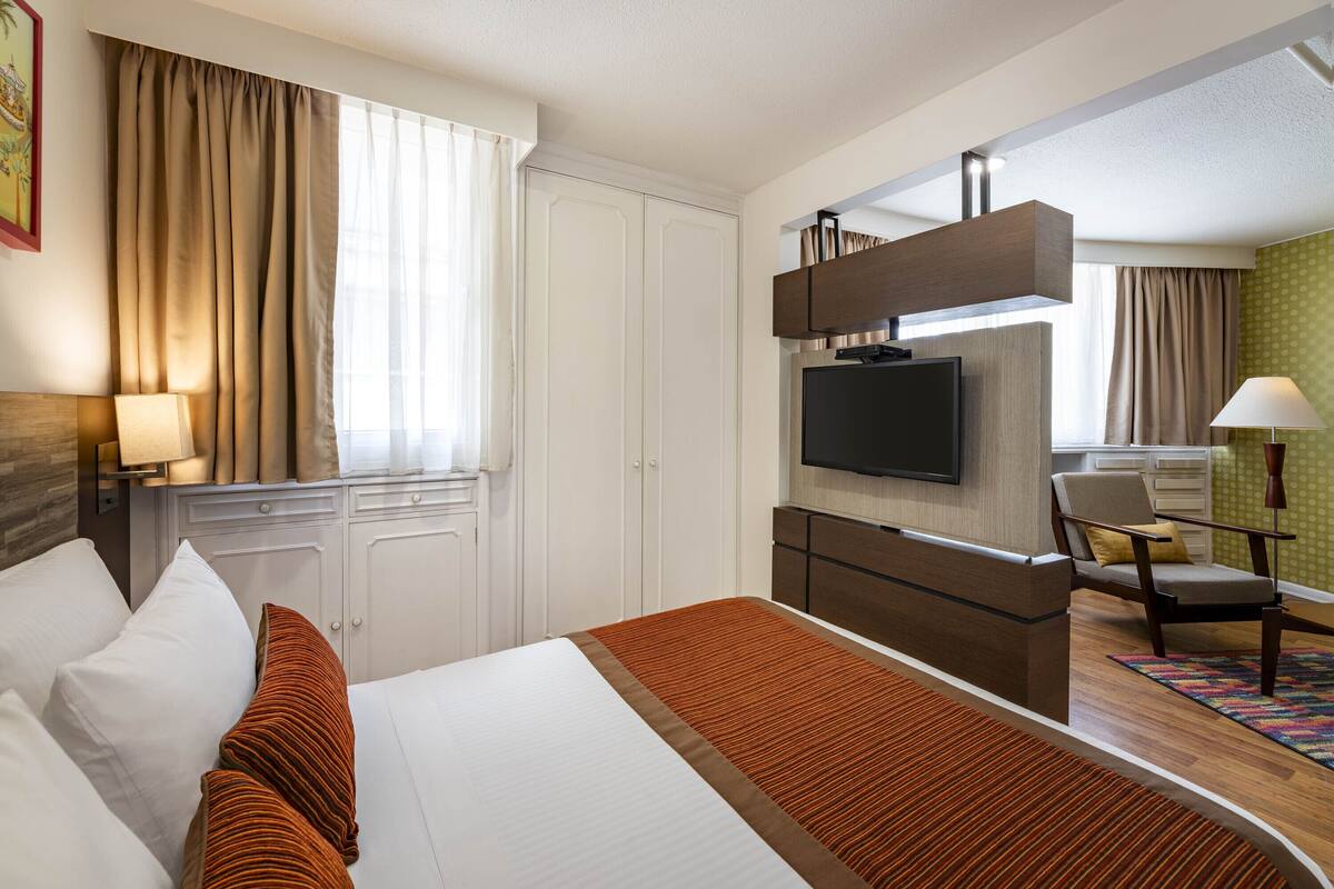 Hotellihuone, jossa on sänky, televisio, työpöytä ja tuoli.