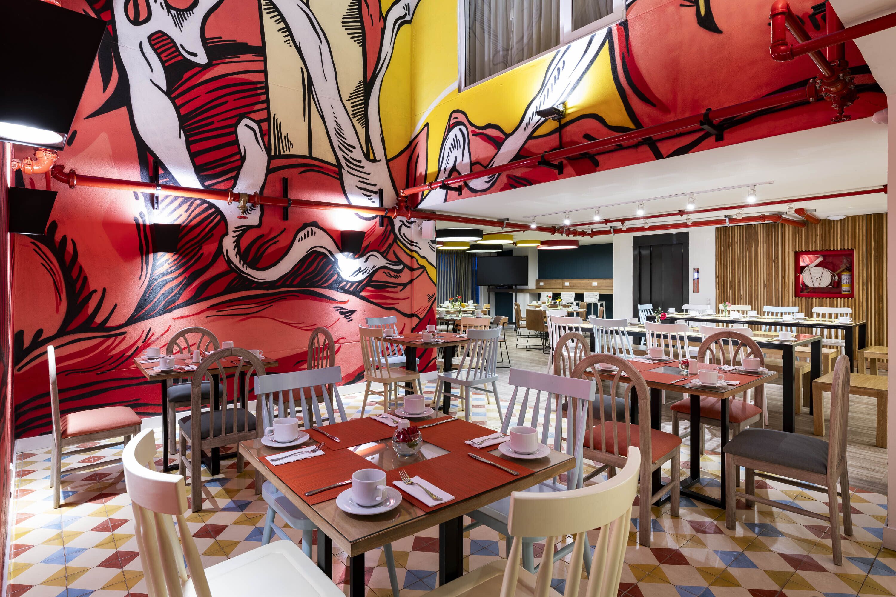 En restaurant med højt til loftet, livlig kunst og møbler i en blanding af træ og metal.