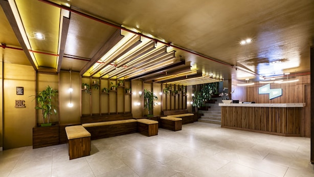 Um lobby moderno com balcão de recepção, áreas de estar e plantas.