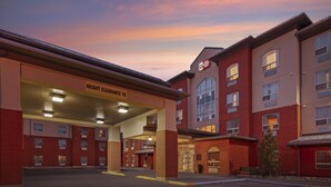 A hotel with a red brick facade, a covered entrance, and a sign indicating a height clearance of 16'. - Best Western Plus Meridian Hotel (Lloydminster)
