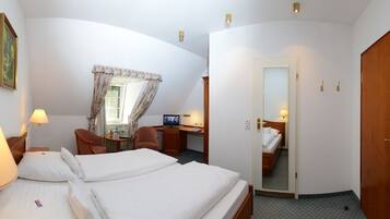 Habitación de hotel con dos camas, un escritorio con computadora, una silla, una lámpara y un ventanal con cortinas.