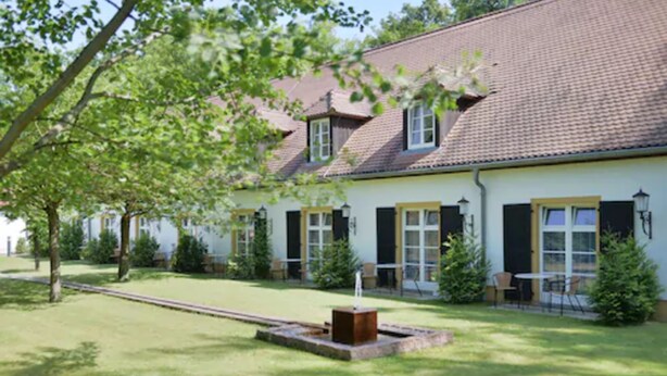 A two-story house with a tiled roof, a well-maintained lawn, and a small garden area with a fountain. - Churfuerstliche Waldschaenke Moritzburg (Moritzburg)