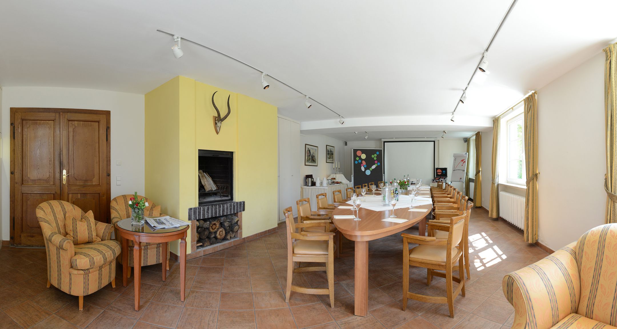 A spacious living room with a fireplace, a dining area with a long table, and a cozy seating arrangement.