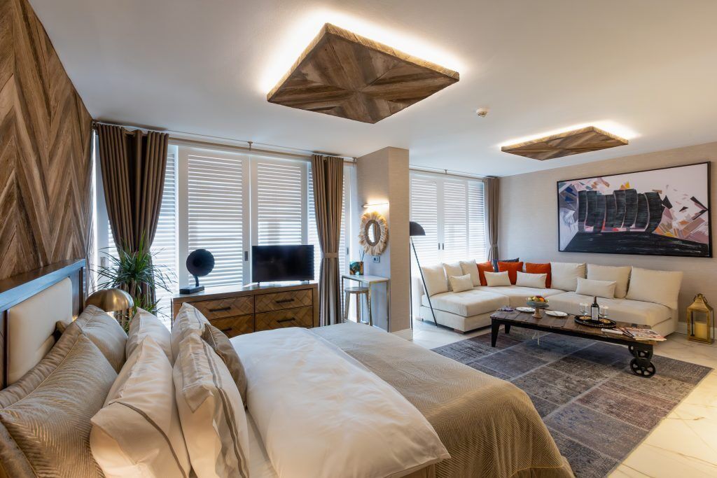 Une chambre d’hôtel moderne avec un grand lit, un canapé, une table basse et un téléviseur.