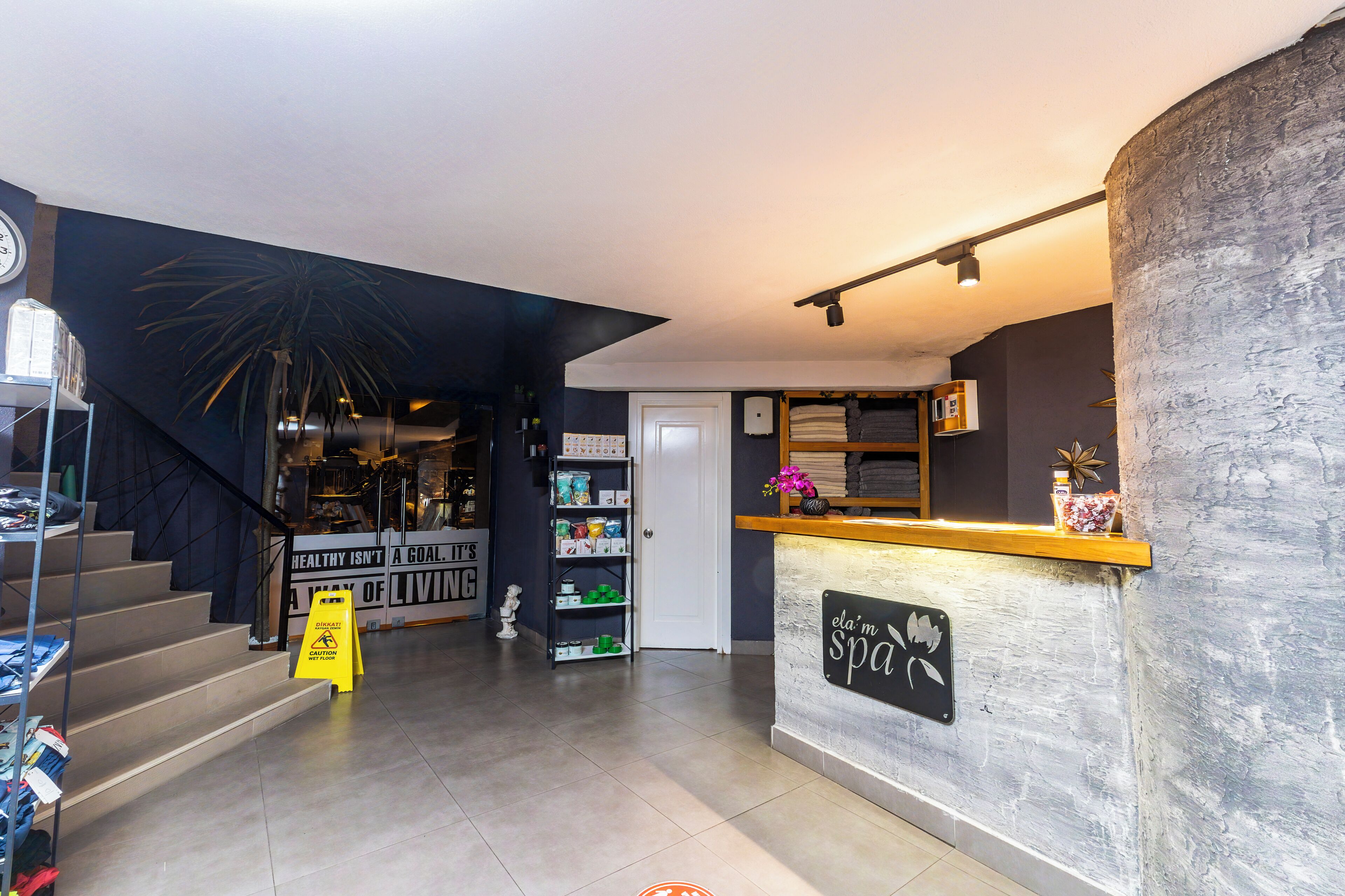 A reception area with a counter, a staircase, and a shelf with various items.