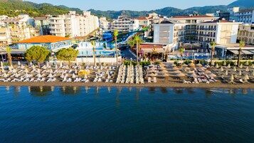 Ένα παραθαλάσσιο ξενοδοχείο με πολλά επίπεδα, ένα υδάτινο πάρκο και πολλά ομπρέλες και ξαπλώστρες στην παραλία.