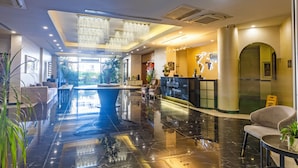 Un moderno vestíbulo de hotel con una recepción, zona de estar y un amplio suelo reflectante.
