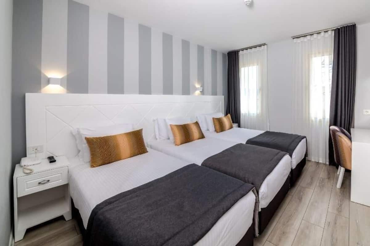 A hotel room with two beds, a desk, a chair, and a TV.