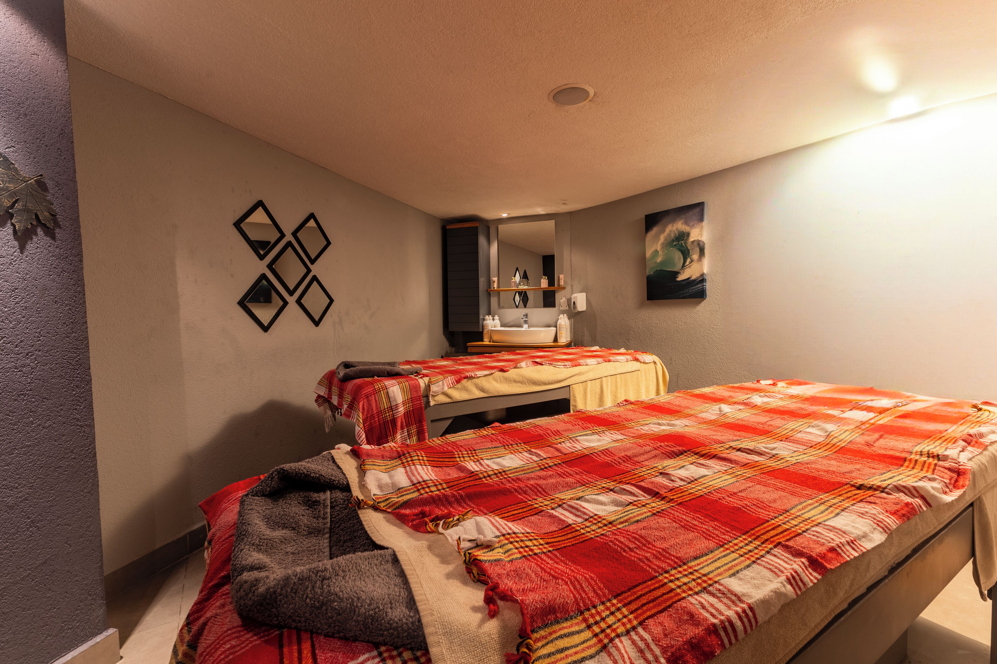 Un dormitorio con dos camas, un baño con lavamanos y un espejo.