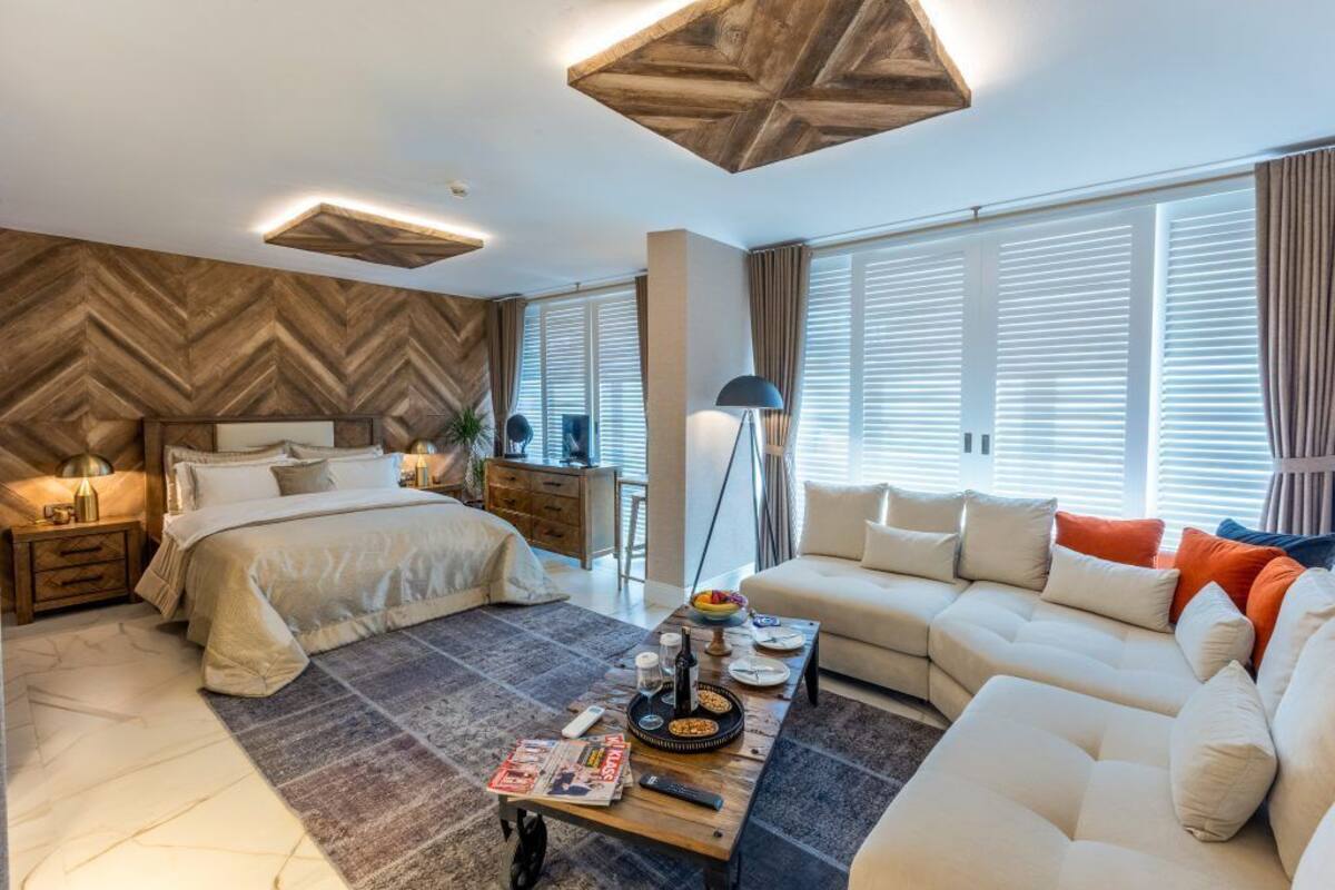 A modern bedroom with a large bed, a sofa, and a dining area.