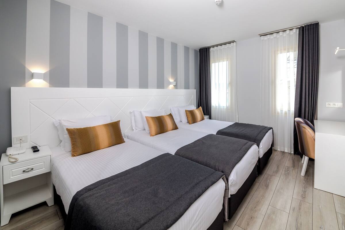 A hotel room with two beds, a desk, a chair, and a TV.