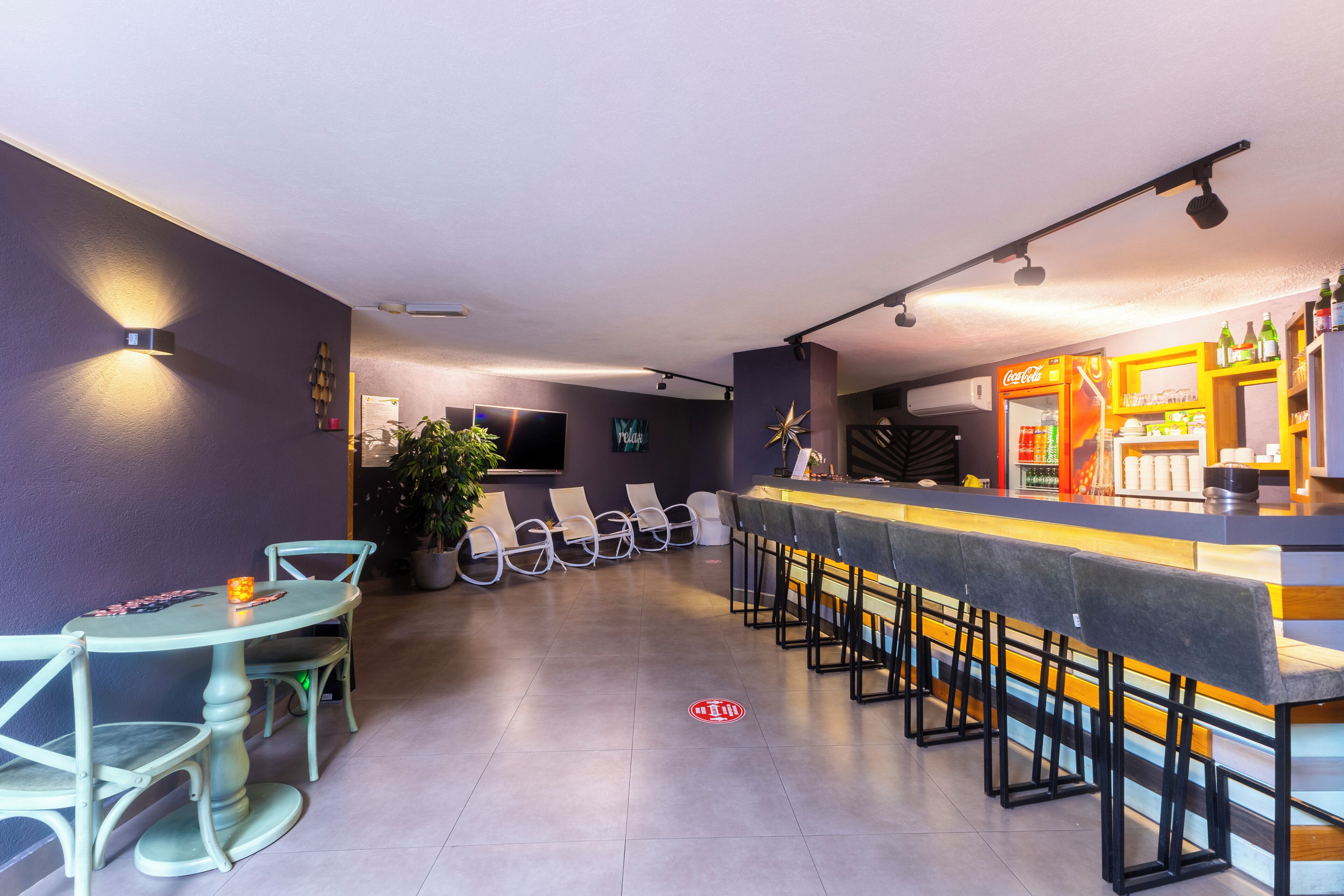 Eine Bar mit Theke, Barhocker und einer Sitzecke mit Stühlen.