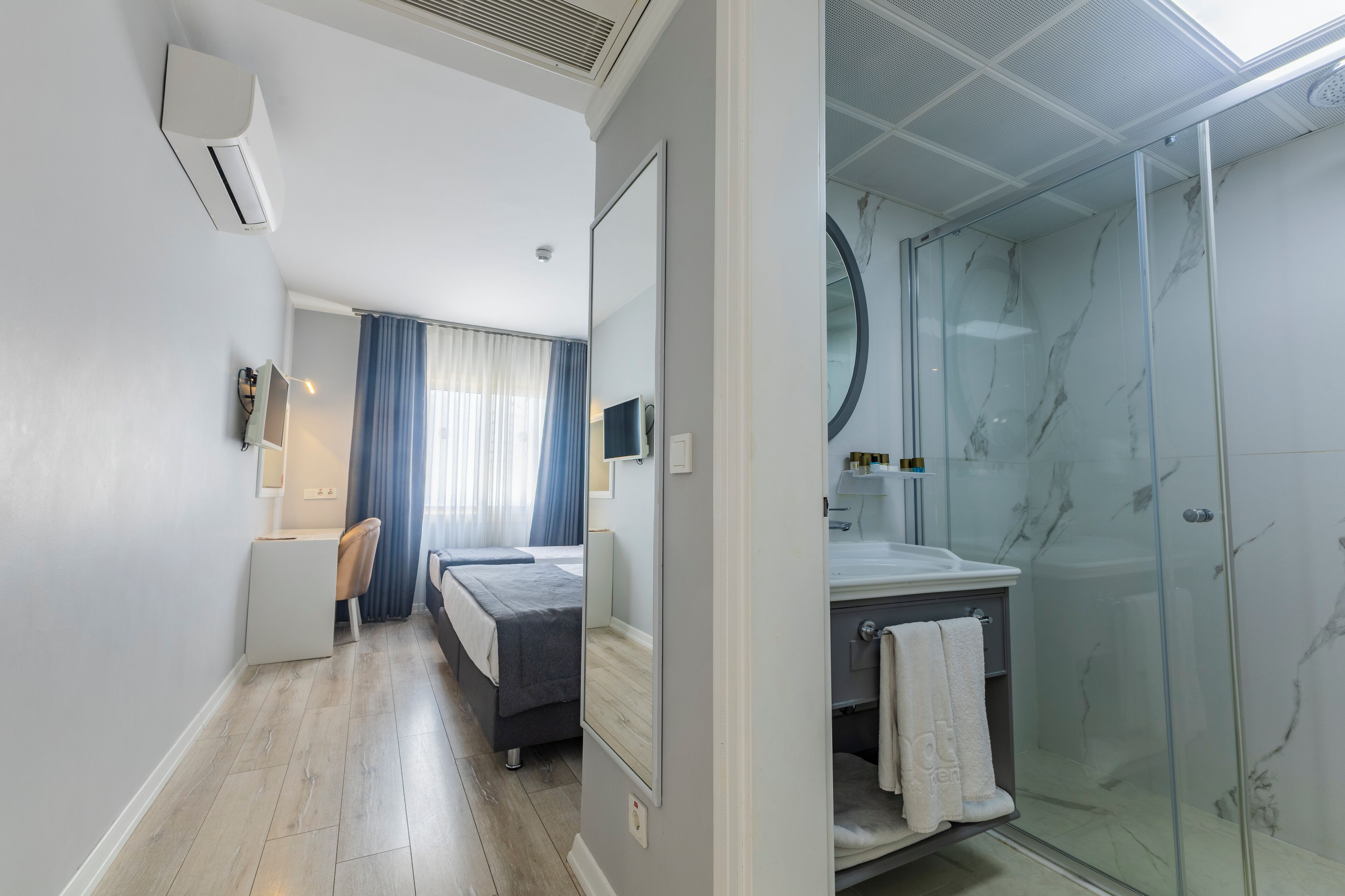 Camera d'albergo moderna con un letto, una scrivania e una cabina doccia in vetro.