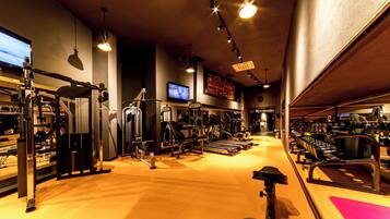 A gym with various exercise equipment, a television, and motivational posters on the walls.