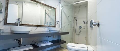 Un baño moderno con un espejo grande, dos lavamanos, inodoro y zona de ducha.