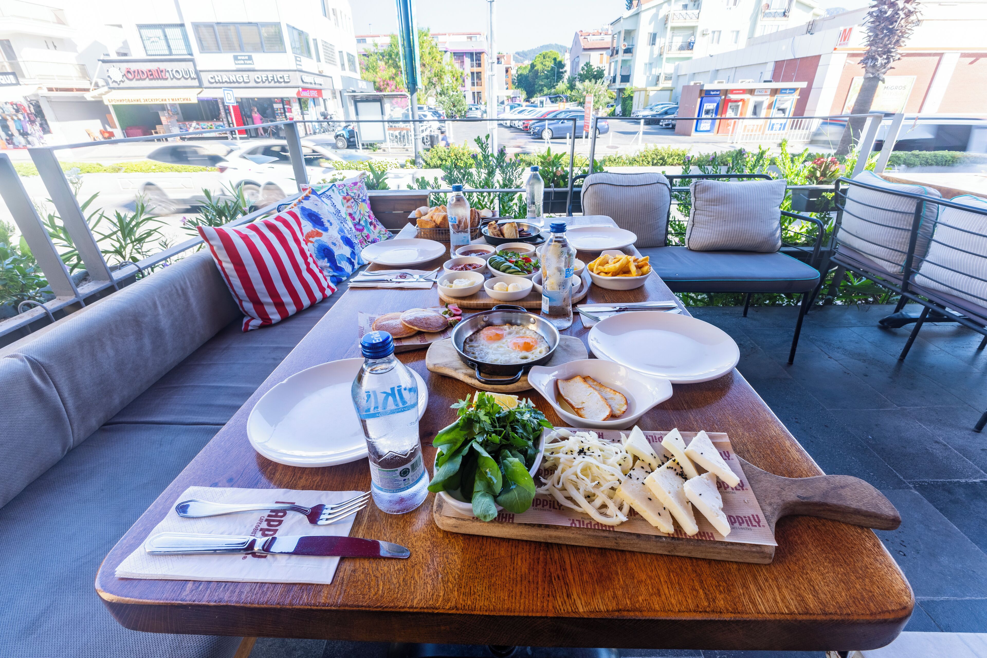 A dining table set with various dishes, a bottle of water, and a wooden cutting board.