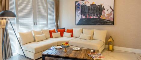 A living room with a sectional sofa, a coffee table, a floor lamp, and a painting on the wall.